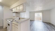 This single-level unit features a clean, functional layout designed for comfortable everyday living. The living area is open and well-proportioned, finished with light gray wood-look flooring that extends throughout the main spaces, complemented by white walls and a textured ceiling. A sliding glass door fills the room with natural light and provides direct access to an outdoor patio, while a front entry door offers a secondary point of access.

The galley-style kitchen is efficiently arranged with white cabinetry lining both sides, providing ample storage above and below the countertops. Light granite-look countertops, a stainless steel sink, a white electric range, a dishwasher, and a full-size refrigerator complete the kitchen's functional setup. A peninsula counter opens toward the living area, creating a connected flow between spaces.

The bedroom offers a comfortable footprint with two windows fitted with blinds, allowing for natural light and ventilation. The textured ceiling and matching wood-look flooring continue throughout.

The bathroom includes a full-size soaking tub and shower combination with white tile surround. A dedicated in-unit laundry closet accommodates a side-by-side washer and dryer, adding notable convenience to the overall layout.