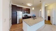 Located at 102 Dalton Lane in Charlottesville, Virginia, this single-floor residence offers a thoughtfully designed open-concept layout that promotes a sense of spaciousness throughout. The kitchen serves as a focal point of the home, showcasing rich dark espresso cabinetry, granite countertops, and a suite of stainless steel appliances including a refrigerator, electric range, and over-the-range microwave. A peninsula with an integrated sink and pendant lighting overhead adds both functionality and visual interest, flowing seamlessly into the adjoining living area.

The living and dining areas feature neutral-toned carpeting that extends into the bedrooms, contributing to a warm, cohesive aesthetic. Multiple windows fitted with horizontal blinds invite abundant natural light throughout, while ceiling fans in the bedrooms and living spaces enhance comfort year-round. Track lighting in the main living area adds a practical yet modern touch.

The bathrooms are finished with wood-look flooring, dark cabinetry with granite countertops, and full tub-shower combinations with curved curtain rods. One bathroom features a dual-vanity configuration, offering additional convenience. Crisp white walls and clean lines throughout maintain a bright, neutral palette, making the space versatile and move-in ready.