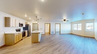 Located at 3277 Birch St in Eau Claire, Wisconsin, this single-floor, 2-bedroom, 2-bathroom residence offers a thoughtfully designed open-concept layout with consistent light-toned luxury vinyl plank flooring throughout. The combined kitchen and living area forms the heart of the home, anchored by a central kitchen island with an integrated sink and pendant lighting above. The kitchen features light wood cabinetry, white countertops, and a full suite of stainless steel appliances, including a refrigerator, range, and built-in microwave. Recessed lighting and a ceiling fan enhance the bright, airy atmosphere of the living space, which also benefits from natural light through a window. The primary bedroom is a comfortable retreat with a ceiling fan, a closet, and direct access to a private bathroom featuring a walk-in shower, single-sink vanity with wood cabinetry, and clean white finishes. The second bedroom also includes a ceiling fan, a window with an outdoor view, and a built-in closet with sliding doors. A dedicated laundry area houses a stacked washer and dryer unit with additional shelving. A connecting hallway provides organized access to all rooms, completing this practical and well-finished residence.