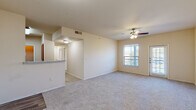 This single-story, 2-bedroom, 1-bathroom home offers a functional and comfortable layout across its well-utilized floor plan. The open-concept living room and kitchen area form the heart of the home, with plush carpeting underfoot and a ceiling fan with light kit overhead. Natural light streams in through windows fitted with blinds, and a exterior door provides convenient access. The kitchen is separated from the living area by a breakfast bar with granite-style countertops, and features rich dark wood cabinetry, wood-look vinyl flooring, a double-basin stainless steel sink, and white appliances including an electric range, built-in microwave, and dishwasher. Both bedrooms are carpeted and equipped with ceiling fans, offering a comfortable and quiet retreat. Each room features windows that allow in natural light and closet access nearby. The primary bedroom provides a modest but practical space. The bathroom includes a tub-shower combination with white and tan tile surround, safety grab bars, and wood-look flooring. Additional storage is available through two closets and a utility room, rounding out this thoughtfully organized home.