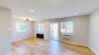 This two-story home offers a practical and well-designed layout spread across two floors. The main level hosts a spacious open-plan living and dining area distinguished by light hardwood flooring, recessed lighting, and multiple windows that flood the space with natural light. A sliding glass door provides direct access to the outdoors, enhancing the sense of openness. The kitchen is efficiently laid out and features stainless steel appliances — including a gas range, over-the-range microwave, and refrigerator — paired with white shaker-style cabinetry and granite-look countertops. Also on the main floor is a full bathroom with a vanity, mirror cabinet, and dark-finish fixtures. A staircase with a black metal railing connects both levels. The upper floor is home to two bedrooms, each carpeted for comfort and equipped with wall-mounted HVAC units. The primary bedroom is generously proportioned and includes a closet, ceiling fixture, and a window with neighborhood views. The secondary bedroom is cozy with soft carpeting and a ceiling fan. A second full bathroom on this level features a tiled shower/tub, window with blinds, and matte black hardware. Neutral tones and clean finishes throughout lend the home a bright, move-in-ready feel.