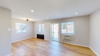 This two-story home offers a practical and well-designed layout spread across two floors. The main level hosts a spacious open-plan living and dining area distinguished by light hardwood flooring, recessed lighting, and multiple windows that flood the space with natural light. A sliding glass door provides direct access to the outdoors, enhancing the sense of openness. The kitchen is efficiently laid out and features stainless steel appliances — including a gas range, over-the-range microwave, and refrigerator — paired with white shaker-style cabinetry and granite-look countertops. Also on the main floor is a full bathroom with a vanity, mirror cabinet, and dark-finish fixtures. A staircase with a black metal railing connects both levels. The upper floor is home to two bedrooms, each carpeted for comfort and equipped with wall-mounted HVAC units. The primary bedroom is generously proportioned and includes a closet, ceiling fixture, and a window with neighborhood views. The secondary bedroom is cozy with soft carpeting and a ceiling fan. A second full bathroom on this level features a tiled shower/tub, window with blinds, and matte black hardware. Neutral tones and clean finishes throughout lend the home a bright, move-in-ready feel.