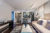 Located in the Parkwood Circle SE community in Atlanta, Georgia, this single-floor residence combines modern finishes with a warm, inviting atmosphere. The kitchen is a standout feature, outfitted with grey shaker-style cabinetry, granite countertops, and a full suite of stainless steel appliances including an electric range, microwave, and refrigerator. A peninsula with seating offers a casual dining option, while pendant lighting and a subway tile backsplash add contemporary style. Dark hardwood-style flooring runs throughout, providing a cohesive and elegant look. The bedroom is a relaxing retreat, featuring direct access to a private balcony through glass French doors that invite natural light and outdoor views. The room is generously proportioned and exudes a calm ambiance with neutral tones and warm accent lighting. The bathroom is finished with granite countertops on grey vanity cabinetry, tile flooring, and a full tub-shower combination with floor-to-ceiling tile surround. The overall design of this residence balances functionality and comfort, with thoughtful details and quality finishes throughout that create a refined, modern living environment.