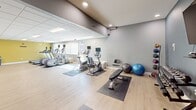 This 840 square foot fitness center, located in West Des Moines, Iowa, offers a comprehensive workout experience. The space is divided into distinct areas for cardio, strength training, and functional exercises. It features state-of-the-art equipment including treadmills, ellipticals, weight machines, and free weights. The room is enhanced by large wall-mounted TVs, mirrored walls, and a bright color scheme with blue and yellow accents. The facility also includes exercise balls, resistance bands, and a dedicated stretching area. With its spacious layout and variety of equipment, this gym caters to a wide range of fitness needs and preferences.