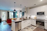 Located at 2801 Windy Ridge Pky SE in Atlanta, GA, this thoughtfully designed 2-bedroom, 2-bathroom residence offers a modern living experience across a single, efficiently arranged floor. The open-concept kitchen is a standout feature, outfitted with crisp white shaker cabinetry, a herringbone tile backsplash, dark countertops, stainless steel appliances including a full-size refrigerator, range, microwave, and dishwasher, and a central island with a matte black faucet — all illuminated by stylish pendant lighting. The living area flows naturally from the kitchen and is bathed in natural light from large windows, with direct access to a private balcony offering outdoor views of surrounding greenery. Each bedroom is carpeted for comfort, featuring natural light through generous windows and dedicated closet space — three closets are distributed throughout the unit, including wire-shelved walk-in storage. The primary bathroom features a wide vanity with dark countertops, white cabinetry, black hardware, and wood-look flooring, while the second bathroom includes a tub with wood-toned tile surround. A dedicated utility room and durable wood-look flooring in the main living areas complete this well-finished residence.