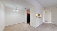 Located at 3750 Peachtree Industrial Blvd in Duluth, Georgia, this single-floor residence offers a well-organized layout designed for comfortable everyday living. The open living and dining areas are finished with plush carpeting and neutral tones throughout, creating a bright and welcoming atmosphere. A elegant chandelier accents the dining space, while the adjacent living room benefits from vaulted-style ceilings that lend a sense of openness. A pass-through window connects the living and dining areas to the kitchen, which features warm cherry-toned cabinetry, dark granite-style countertops, wood-look flooring, and black appliances including a range and refrigerator. A dedicated laundry area is conveniently accessible directly from the kitchen. The bedrooms are generously sized, each finished with soft carpeting and large windows that invite ample natural light. One bedroom includes sliding glass doors opening to an outdoor area, complemented by a ceiling fan for added comfort. The bathrooms are appointed with rich wood-toned vanities, granite-style countertops, wood-look flooring, and tiled shower-tub combinations. Closet storage is well-distributed throughout the residence, adding to its functional and practical design.