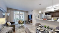 Located at 4400 NW 79th Ave in Doral, Florida, this single-floor residence offers a thoughtfully designed open-concept layout that seamlessly connects the living, dining, and kitchen areas. The living room is bright and welcoming, featuring large sliding glass doors dressed with floor-to-ceiling sheer curtains that invite natural light and provide views of the outdoor surroundings. A built-in wood media wall serves as a focal point, complementing the light-toned tile flooring found throughout the unit. The dining area sits adjacent to the kitchen, anchored by a glass-top table and pendant lighting overhead. The kitchen is well-appointed with dark espresso cabinetry, granite countertops, stainless steel appliances including a refrigerator, range, microwave, and dishwasher, and a breakfast bar that connects the cooking space to the dining area. The primary bedroom is generously proportioned, featuring large windows with lush outdoor greenery views, ample closet space, and a private en-suite bathroom with a dark-vanity, mirror, and tub-shower combination. A second bedroom mirrors a similar layout with a mirrored sliding closet and natural light. A second full bathroom with matching dark cabinetry and a tub-shower completes the space. The overall aesthetic is clean, contemporary, and well-finished throughout.