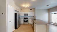 This single-floor residence offers a thoughtfully designed layout that balances functionality with modern style. The kitchen is a standout feature, equipped with stainless steel appliances including a refrigerator, electric range, and over-the-range microwave. Crisp white shaker-style cabinetry lines the walls, complemented by a light blue subway tile backsplash and dark quartz-style countertops that extend to a peninsula, providing additional workspace and storage. Light wood-tone luxury vinyl plank flooring runs throughout the kitchen and into the main living areas, adding warmth and easy maintenance.

The living area is generously proportioned and filled with natural light from a set of French doors flanked by windows, offering a view to the outdoors. A ceiling fan overhead enhances comfort. The entry area features neutral grey walls and a clean, open feel with the same light flooring extending seamlessly.

The bedroom is a quiet retreat with darker wood-tone vinyl plank flooring, neutral walls, and a ceiling fan. The bathroom includes a full soaking tub and shower combination with white tile surround and brushed nickel hardware. Throughout the space, neutral tones, consistent flooring, and modern fixtures create a cohesive and move-in-ready living environment.
