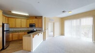 This single-floor residence offers a thoughtfully designed open-concept layout that seamlessly connects the kitchen and living areas. The kitchen is equipped with warm honey-toned wood cabinetry, granite countertops, stainless steel appliances including a gas range and microwave, and a peninsula with bar seating that serves as a natural divider between the kitchen and the carpeted living space. The living area is bright and spacious, featuring warm beige walls, plush neutral carpeting, and large vertical-blind-covered sliding doors that invite natural light and provide access to an outdoor balcony with greenery views.

The bedrooms are carpeted and finished with clean white walls, offering a calm and comfortable atmosphere. At least one bedroom features mirrored sliding closet doors with built-in shelving and hanging rods, maximizing storage. The bathrooms are well-appointed, with one featuring granite countertops, wood cabinetry, a skylight, built-in open shelving, a large vanity mirror, and a glass-enclosed bathtub and shower combination finished in neutral tile. A second bathroom also includes a glass-sliding-door tub and shower enclosure with clean white tile surround. Throughout the residence, consistent finishes and a neutral color palette create a cohesive and welcoming ambiance.