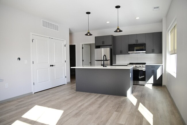 A modern kitchen with a large island and pendant lights. - The Guild
