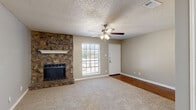 This single-story, 2-bedroom, 2-bathroom home offers a practical and comfortable layout across a well-proportioned floor plan. The living room serves as the heart of the home, anchored by a striking floor-to-ceiling stacked stone fireplace with a white mantel. A ceiling fan with integrated lighting, plush carpet flooring, and a window allowing natural light create a warm and inviting atmosphere. An adjacent entry door provides direct outdoor access.

The kitchen features warm wood-toned cabinetry, white countertops, and wood-look flooring. Equipped with a black electric range, dishwasher, and a window overlooking the outdoors, it is both functional and efficient. A secondary area with wood-look flooring and French doors leading outside offers flexible use as a dining or sitting space.

Both bedrooms are carpeted and include ceiling fans with light fixtures. The spacious primary bedroom features a large window for natural light and direct access to a walk-in closet with dual hanging rods and shelving. The second bedroom is comparably sized with its own ceiling fan.

Each bathroom includes wood-look flooring, a single vanity with warm wood cabinetry, a mirror with overhead lighting, and a tub-shower combination. Throughout the home, textured ceilings and neutral-toned walls provide a cohesive, move-in-ready aesthetic.