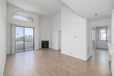 Located in the desirable Westwood neighborhood of Los Angeles, this 2-bedroom, 3-bathroom residence offers a bright and airy living experience defined by thoughtful design and quality finishes throughout. The living room immediately impresses with its dramatic vaulted ceilings, a distinctive arched transom window that floods the space with natural light, and light-toned hardwood flooring. A corner fireplace adds warmth and character, while sliding glass doors open to a balcony with sweeping views of palm trees and the surrounding cityscape. The open-concept layout connects the living area seamlessly to the kitchen, which is outfitted with stainless steel appliances—including a gas range, built-in microwave, and refrigerator—white cabinetry, light stone countertops, and tile flooring. A pass-through counter enhances the connection between the kitchen and living spaces. Both bedrooms are well-proportioned, featuring hardwood floors and large windows that frame views of the Los Angeles skyline and lush neighborhood greenery. The primary bedroom offers generous space for comfortable furnishing. The three bathrooms are cleanly finished, with one featuring a tiled tub-shower combination with a glass enclosure, and another with a walk-in tiled shower and stone-topped vanity. The overall ambiance is clean, modern, and light-filled throughout.