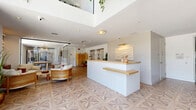 Located at 10401 Washington Blvd in Culver City, CA, this single-floor commercial space offers a thoughtfully designed environment that balances professionalism with warmth. The entrance greets visitors with dramatic double-height ceilings, floor-to-ceiling glass windows, and a striking geometric patterned floor that flows throughout the space. Cascading greenery suspended from above adds a lively, biophilic touch that complements the bright, airy atmosphere.

At the heart of the space is a sleek reception desk finished in white with natural wood countertops, accented by a textured wave wall art piece. The open layout beyond the reception includes a lounge area furnished with rattan seating, gold-toned pendant lighting, and curated décor that reinforces the space's warm, modern aesthetic.

A dedicated conference room, accessible via glass-partitioned walls, features a long natural wood table surrounded by ergonomic seating, a wall-mounted display, and an eye-catching gold orbital chandelier. Large windows allow abundant natural light to filter in, while sheer drapery provides privacy when needed. Potted tropical plants in gold planters add a sophisticated, organic element throughout. The space is well-suited for a professional office or client-facing business environment.