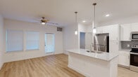 Located at 13030 Perry Road in Houston, TX 77070, this single-story, one-bedroom, one-bathroom unit offers a thoughtfully designed layout with contemporary finishes throughout. Light wood-style flooring runs seamlessly across all rooms, creating a clean and cohesive aesthetic.

The open-concept kitchen is a standout feature, boasting granite countertops, white shaker cabinetry, a herringbone tile backsplash, and a full suite of stainless steel appliances including a refrigerator, range, and microwave. A large kitchen island with an undermount sink and pendant lighting overhead serves as both a functional workspace and a natural gathering point. A built-in desk nook adds extra utility to the kitchen area.

The living area flows naturally from the kitchen and is equipped with a ceiling fan, recessed lighting, and a private exterior door that invites natural light into the space.

The bedroom is a comfortable, well-proportioned room featuring two windows with blinds, a ceiling fan, and access to a spacious walk-in closet outfitted with multi-level wire shelving for generous storage.

The bathroom includes a granite vanity, a soaking tub with marble-style tile surround, and direct access to the walk-in closet. The overall design palette of white walls, light flooring, and neutral tones lends the space a bright, modern, and welcoming ambiance.