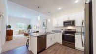 This thoughtfully designed single-floor residence at 95 Salmon Brook St in Granby, Connecticut offers a clean, contemporary living experience with an open and airy layout. The kitchen is a standout feature, showcasing white shaker cabinetry, granite countertops, a peninsula with bar seating, and a full suite of stainless steel appliances including a range, microwave, dishwasher, and refrigerator. Pendant lighting above the peninsula adds a refined touch, while wood-look flooring throughout the kitchen and entry areas provides durability and warmth. The kitchen flows seamlessly into the living area, which is filled with natural light from large windows and features plush carpet flooring, crown molding, and ample space for both lounging and a dedicated workspace. The bedroom is a serene retreat, appointed with soft carpet, generous closet access, and a calm, neutral palette that promotes restful living. The bathroom is well-equipped with a white vanity, a tub-shower combination with a curtain enclosure, and wood-look tile flooring that ties the space together. Throughout the residence, the consistent use of white finishes, neutral tones, and modern fixtures creates a cohesive and inviting atmosphere suited for comfortable everyday living.