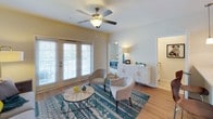 This single-floor residence offers a thoughtfully designed layout that balances comfort and functionality throughout. The living room serves as the heart of the home, featuring light hardwood flooring, a ceiling fan, and large French doors fitted with plantation shutters that invite an abundance of natural light and provide access to an outdoor area. A cozy seating arrangement and vibrant décor accents give the space a welcoming ambiance.

Adjacent to the living area, the dining space is defined by a warm-toned round wooden table, modern white chairs, and an elegant chandelier overhead — ideal for everyday meals or entertaining guests.

The kitchen is well-equipped with white cabinetry, granite countertops, stainless steel appliances including a refrigerator, range, and dishwasher, along with pendant lighting and hardwood-style flooring. A washer is conveniently located within the kitchen area, adding practical in-unit laundry access.

The bedrooms are carpeted and bright, each featuring ceiling fans and generous windows — one notably showcasing a striking arched window design that floods the room with outdoor views and natural light.

The bathrooms are finished with granite-topped white vanities, tile flooring, and clean, neutral walls, offering a polished and functional design. Together, these spaces create a cohesive, comfortable living environment.
