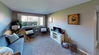 This single-floor residence offers a thoughtfully designed layout that balances comfort and functionality. The living area is a welcoming space anchored by plush carpeting and a large picture window that frames views of the surrounding greenery, flooding the room with natural light. Two sleek accent chairs and a media console make it ideal for both relaxing and entertaining.

The kitchen is efficiently laid out with crisp white shaker cabinetry, granite-look countertops, and stainless steel appliances including a smooth-top range and a full-size refrigerator. Warm wood-style flooring adds a polished touch to the space.

The primary bedroom is generously sized, featuring soft carpeting, neutral gray walls, and a walk-in closet with a built-in rod and shelving. A bedside lamp provides warm ambient lighting, enhancing the room's cozy atmosphere. The second bedroom also offers carpeted flooring, a window with vertical blinds that bring in natural light, and ample space for a dresser and additional furnishings.

The bathroom is finished with a granite-topped vanity, white cabinetry, a framed mirror, and wood-style flooring. A full shower-tub combination completes the space. Throughout the residence, a consistent neutral color palette ties each room together, creating a cohesive and inviting environment.
