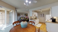 This single-floor unit offers a practical and comfortable layout designed for everyday living. The open-concept dining area connects seamlessly to the living room and kitchen, creating a cohesive communal space. The dining area features carpet flooring, a ceiling fan with integrated lighting, and a window that invites natural light and outdoor views. Adjacent to the dining space, the galley-style kitchen is outfitted with white cabinetry, laminate countertops, white appliances including a refrigerator and electric range, and warm hardwood flooring. A pass-through opening connects the kitchen to the dining area, enhancing the sense of openness.

The living room provides a comfortable retreat with plush carpet, neutral walls, and a textured ceiling. Two bedrooms offer restful accommodations; the primary bedroom includes mirrored sliding closet doors and carpet flooring, while the second bedroom is equally well-proportioned with carpet and a window for natural light. The bathroom features a wide vanity with a composite countertop, an extended mirror, and hardwood flooring at the entry. Textured ceilings are consistent throughout the unit.