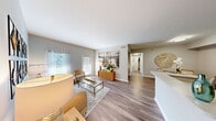 This thoughtfully designed 2-bedroom, 2-bathroom single-floor residence offers a functional and inviting layout across a generously sized floor plan. Wide-plank wood-style flooring flows throughout, lending warmth and continuity to every room.

The open-concept living area is bright and welcoming, with natural light streaming through large windows dressed in patterned curtains. It connects seamlessly to a dedicated dining area, ideal for everyday meals or entertaining. The kitchen features white cabinetry, stainless steel appliances including a refrigerator, range, and microwave, plus a peninsula counter that opens to the main living space.

A hallway leads to both bedrooms, each offering generous closet space — with a total of four closets throughout the home providing ample storage. The spacious primary bedroom is complemented by its own bathroom, while a second full bathroom serves the additional bedroom and guests. Both bathrooms are finished in neutral tones with clean white fixtures, vanity storage, and tub-shower combinations with wood-style flooring.

A dedicated in-unit laundry area houses a full-size washer and dryer with built-in shelving above. The private balcony extends the living space outdoors, offering a relaxing retreat. A welcoming entrance and central hallway round out this well-organized, move-in-ready home.