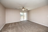 This single-floor, one-bedroom residence offers a practical and comfortable layout across a compact yet efficiently organized floor plan. The living area is carpeted and bright, featuring a ceiling fan with a light fixture and sliding glass doors that open onto a private balcony, allowing natural light to fill the space and providing pleasant outdoor views. A bold, dark front door adds a striking contrast to the neutral-toned walls and soft carpeting throughout.

The kitchen is equipped with rich, warm-toned wood cabinetry — both upper and lower — paired with light countertops, a stainless steel sink, and a dishwasher. Wood-look flooring in the kitchen adds a clean, durable finish that transitions seamlessly into the adjacent areas.

The bedroom is a comfortable size, finished with plush carpeting, neutral walls, a ceiling fan, and a window fitted with blinds that allow for natural light and privacy. A dedicated closet provides convenient storage.

The bathroom features wood-look tile flooring, a warm wood vanity with a white countertop, and a stacked washer and dryer unit, offering the added convenience of in-unit laundry. The layout is clean and functional, making efficient use of the available space. Overall, the residence presents a cohesive, neutral aesthetic with practical finishes throughout.