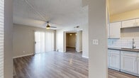 This single-floor, 2-bedroom, 1-bathroom residence offers a thoughtfully designed layout with clean, modern finishes throughout. Light-toned luxury vinyl plank flooring runs consistently across all rooms, complementing the neutral warm-gray wall palette and crisp white trim.

The open-concept kitchen is a standout feature, equipped with white shaker-style cabinetry, dark quartz countertops, a classic white subway tile backsplash, and a full suite of stainless steel appliances including a refrigerator, range, microwave, and dishwasher. A peninsula with matching countertop provides additional prep space and a natural transition into the living area. Track lighting and vaulted ceiling details add visual interest to the kitchen.

The living room is bright and inviting, featuring a ceiling fan, textured ceiling, and a sliding glass door dressed with vertical blinds that allows abundant natural light to fill the space.

Both bedrooms are comfortably sized, each featuring ceiling fans, textured ceilings, and windows with horizontal blinds. The spacious primary bedroom includes its own closet. The full bathroom features white cabinetry, a quartz-topped vanity, and a separate water closet. Two closets throughout the home offer practical storage solutions.