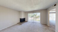 This single-floor, one-bedroom, one-bathroom unit offers a practical and comfortable layout across a compact yet efficiently designed floor plan. The entry opens into a hallway that transitions seamlessly between the living spaces, with wood-look flooring at the threshold giving way to plush carpet throughout the main living areas.

The combined kitchen and living room serves as the heart of the unit. The living area is highlighted by a raised-hearth fireplace with a dark surround, adding a cozy focal point to the room. A large sliding glass door fitted with vertical blinds fills the space with natural light and provides views of the surrounding greenery outside. The kitchen features a peninsula counter with a speckled laminate surface, warm wood-toned upper cabinets, a white electric range, a double-basin stainless steel sink, and a full-size refrigerator, all set on wood-look flooring.

The spacious primary bedroom is carpeted and includes a sliding closet and its own sliding glass door with vertical blinds, allowing for additional natural light and outdoor access. The bathroom is clean and functional, offering a full tub-shower combination with tile surround, a vanity with a speckled countertop, and wood-look flooring. A textured ceiling is consistent throughout the unit, completing the space.