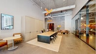 Located at 625 North 2nd Avenue in the heart of Phoenix, this single-floor commercial space offers a sophisticated blend of industrial and contemporary design across a generously proportioned open floor plan. Soaring ceilings with exposed ductwork, conduit, and structural elements lend an authentic urban character, while polished concrete floors tie the space together with a clean, modern aesthetic.

A striking X-shaped neon light fixture in warm amber tones serves as a bold artistic centerpiece, complemented by sleek pendant drum lights that illuminate the mailroom and lounge areas. The main collaborative zone features a substantial conference table with a dark steel base and light wood top, surrounded by contemporary seating and flanked by built-in light wood cabinetry offering ample storage.

A glass-partitioned work area provides a semi-private workspace with street-facing views, flooding the interior with natural light. The lounge zone offers curved, upholstered seating in warm neutral tones alongside decorative plants, including a distinctive tall cactus, adding a nod to the Arizona landscape. A dedicated mailroom houses rows of individual lockboxes beneath a cluster of modern pendant lights. Raw concrete accent walls, black-framed glass doors, and thoughtful décor throughout create an inviting, design-forward atmosphere well-suited for a dynamic professional environment.