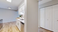 This well-appointed 2-bedroom, 2-bathroom residence in Wayzata, Minnesota offers a thoughtfully designed single-floor layout that balances comfort and functionality. The spacious living room is a standout feature, showcasing light hardwood flooring, a textured ceiling, and a large sliding glass door that opens to a private balcony, filling the space with natural light and offering views of the surrounding landscape. The galley-style kitchen is efficiently laid out with crisp white shaker cabinets, a subway tile backsplash, light countertops, a stainless steel sink, and stainless steel appliances including a dishwasher, range, and refrigerator. The kitchen connects seamlessly to the living area via a half-wall partition. Both bedrooms are generously sized and feature plush neutral carpeting, soft tones, and natural light. The primary bedroom offers ample room and includes closet access. The two bathrooms are finished with white vanities, clean countertops, brushed nickel hardware, and light hardwood-style flooring. Soft, neutral color palettes throughout lend the home a calm, cohesive ambiance. Two hallways provide practical flow between the home's rooms, making the overall layout feel organized and accessible.