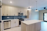 Located at 112 Point Place in Mooresville, NC, this thoughtfully designed single-floor residence offers a seamless blend of modern aesthetics and functional living. The open-concept layout connects the kitchen and living area, creating an inviting, airy atmosphere enhanced by light hardwood flooring throughout.

The kitchen is a standout feature, showcasing light wood cabinetry, a bold blue tile backsplash, stainless steel appliances, and a generous central island with a clean white countertop. Pendant lighting above the island adds a refined touch, while recessed lighting ensures the space is well-lit.

The living area flows naturally from the kitchen and benefits from access to the outdoors through double doors, allowing natural light to fill the room. A ceiling fan overhead adds comfort and practicality.

The bedroom is a comfortable, well-proportioned retreat with large windows fitted with blinds, a ceiling fan, and soft neutral walls that create a calm atmosphere. An adjacent closet provides dedicated storage.

The bathroom is elegantly appointed with a tub-shower combination clad in dramatic marble-style tile featuring warm gold veining, complemented by a frameless sliding glass door and light wood-tone flooring, tying the space together with a sophisticated, contemporary finish.