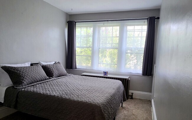 Cómodo dormitorio principal con cama tamaño king y grandes ventanales que permiten la entrada de luz natural. - 822 E 4th St