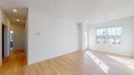 This single-floor unit offers a clean, modern aesthetic defined by crisp white walls, light-toned hardwood flooring, and an abundance of natural light throughout the main living areas. The open-concept living space is generously proportioned, featuring large windows and a glass-paneled entry door that invite sunlight deep into the interior, creating a warm and airy atmosphere.

The kitchen is thoughtfully designed with taupe shaker-style cabinetry, light quartz countertops, a subway tile backsplash, and a full suite of stainless steel appliances including a gas range, microwave, and refrigerator. A peninsula with a breakfast bar provides additional prep space and a natural transition into the living area.

The bedrooms offer comfortable dimensions, with one room featuring soft wall-to-wall carpeting and recessed lighting. Two full bathrooms serve the unit: one includes a sliding glass-enclosed shower stall with marble-style tile flooring and a vanity with warm wood cabinetry, while the second features a combined tub and shower, a matching vanity, and the same elegant tile flooring. Throughout, the unit maintains a cohesive, contemporary palette that is both functional and visually appealing.