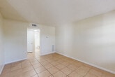 Located at 3545 30th Ave N in Saint Petersburg, Florida, this efficient one-bedroom, one-bathroom unit offers a well-organized single-floor layout. Light-colored ceramic tile flooring runs consistently throughout every room, creating a cohesive, easy-to-maintain interior well-suited to Florida's climate.

The open living area is bright and airy, with neutral cream-toned walls and a textured ceiling. A hallway connects the main living space to the bedroom and bathroom, providing a clear and functional flow. The galley-style kitchen is positioned along one side of the unit and features white cabinetry, a white electric range, and a full-size refrigerator, along with a sink and tile backsplash — offering practical utility in a compact footprint.

The bedroom is a comfortable size, fitted with a ceiling fan, a window that brings in natural light and views of surrounding greenery, and direct access to the hallway. The bathroom includes a full bathtub with white tile surround extending to the walls, and a frosted glass window that allows natural light while maintaining privacy.

Throughout the unit, consistent HVAC venting and wall-mounted heating units ensure year-round comfort. The clean, minimal design and durable finishes make this Saint Petersburg unit a straightforward and functional living space.