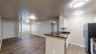 This single-floor residence at 791 29th St NW in Roanoke, Virginia offers a well-organized layout with a clean, modern aesthetic throughout. The open-concept design connects the kitchen and living areas seamlessly, with wood-style plank flooring extending across the main living spaces, creating a cohesive and easy-to-maintain environment.

The kitchen is thoughtfully designed with white shaker-style cabinetry extending to both upper and lower sections, dark granite-look countertops, and stainless steel appliances including a refrigerator and electric range. A peninsula with a built-in sink and additional counter space provides both functionality and a natural division between the kitchen and the open living area. The living space is generously proportioned with neutral-toned walls and flush-mount lighting.

The bedroom features plush carpeting, a large window offering outdoor views and natural light, and access to a spacious walk-in closet equipped with wire shelving and hanging rods on multiple walls. The bathrooms are finished with wood-style flooring, white vanities with single-basin sinks, large mirrors, and brushed nickel fixtures. One bathroom includes a tub-shower combination, while the other serves as a dedicated half bath. The overall ambiance is clean, neutral, and move-in ready.