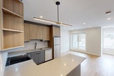 Located in the heart of Calgary's downtown at 909 5 Ave SW, this modern 3-bedroom, 1-bathroom unit offers a thoughtfully designed single-floor layout with contemporary finishes throughout. Light-toned hardwood flooring flows seamlessly across the living areas, hallways, and bedrooms, creating a cohesive and bright interior aesthetic.

The open-concept kitchen is a standout feature, showcasing warm wood-tone cabinetry, a large quartz waterfall island, stainless steel appliances, and a striking linear pendant light with a brass accent. A subway tile backsplash and matte black fixtures add refined modern detail. The kitchen connects directly to the living area, which benefits from a large sliding glass door leading to a private balcony with urban views.

The three bedrooms are finished with neutral tones and light hardwood flooring. Multiple bedrooms feature windows with city views, and select rooms include mirrored sliding closet doors. Five closets throughout the unit provide excellent storage capacity.

The bathroom is finished with marble-style wall tiles surrounding a soaker tub and shower combo, complemented by matte black hardware and white tile flooring. Two hallways and recessed lighting throughout contribute to a clean, organized flow. This well-appointed urban residence offers practical city living with polished modern design.