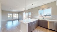 Located at 2155 Kettner Blvd in San Diego's vibrant Little Italy neighborhood, this modern single-floor residence offers a thoughtfully designed open-concept layout filled with natural light. The kitchen is a standout feature, equipped with sleek gray cabinetry, white quartz countertops, stainless steel appliances including a gas range, microwave, dishwasher, and refrigerator, complemented by a central island with pendant lighting overhead. Light wood-style flooring flows throughout the main living areas, connecting the kitchen seamlessly to the spacious living room, which benefits from large windows and sliding glass doors that frame views of the surrounding San Diego cityscape. The bedrooms are carpeted and well-proportioned, each featuring large windows that capture abundant natural light and outdoor views of the city and neighboring treetops, with built-in closets providing practical storage. The bathrooms are finished in a contemporary style, featuring tile flooring, dark wood vanity cabinetry, white quartz countertops, large mirrors, and glass-enclosed walk-in showers. Neutral wall tones and clean lines throughout the residence create a cohesive, modern aesthetic that is both functional and inviting.