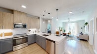 Located at 1909 Alexander Ave in Austin, TX, this well-appointed 2-bedroom, 2-bathroom residence offers a thoughtfully designed open-concept layout across a single floor. Light wood-look flooring flows throughout the common areas, complementing the bright, neutral palette that defines the space.

The kitchen serves as a central hub, featuring gray lower cabinetry, warm wood upper cabinets, a white quartz countertop peninsula with bar seating, stainless steel appliances including a range, microwave, dishwasher, and refrigerator, plus a tile backsplash and statement pendant lighting. It opens seamlessly into the living room, which benefits from a large sliding glass door leading to a private balcony, filling the space with abundant natural light.

The primary bedroom is a comfortable retreat with a ceiling fan, generous closet storage, and its own en-suite bathroom. The bathrooms are finished with wood-toned vanities, white quartz countertops, backlit LED mirrors, and subway tile surrounds. A spacious walk-in closet with built-in shelving and hanging rods provides ample organization.

The second bedroom mirrors the clean, modern aesthetic with a ceiling fan and natural light from a window. A hallway connects all rooms efficiently, with two closets offering additional storage throughout this well-designed Austin residence.