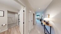This contemporary single-floor residence combines modern design with urban character in a thoughtfully laid-out floor plan. A welcoming hallway with polished concrete floors and recessed lighting connects the various areas of the home, with white doors accented by matte black hardware lending a clean, consistent aesthetic throughout.

The open-plan living and dining area is a standout feature, anchored by large, grid-paned industrial-style windows that frame views of the surrounding cityscape and fill the space with abundant natural light. The living room accommodates comfortable seating and a media setup, while the adjacent dining area features a round wooden table paired with sleek black chairs.

The kitchen is designed for both function and style, showcasing crisp white shaker cabinetry, a classic subway tile backsplash, stainless steel appliances, and a generous marble-veined quartz island with bar seating beneath pendant lighting. This space serves as a natural hub for entertaining and everyday living.

The unit includes two well-proportioned bedrooms, each finished with neutral tones, plush carpeting, and ceiling fans for comfort. An entry foyer with marble-effect flooring and an exposed structural column adds an industrial touch near the front door. Throughout, the neutral color palette, quality finishes, and modern fixtures create a cohesive and refined urban living environment.