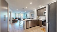 Located at 5420 55th St in San Diego, CA, this thoughtfully designed single-story home offers six bedrooms and four bathrooms across a well-organized floor plan. The open-concept kitchen and living area serves as the heart of the home, featuring dark wood cabinetry, white quartz countertops, stainless steel appliances — including a refrigerator, electric range, microwave, and dishwasher — and a peninsula island with bar seating. Light wood-style flooring runs throughout the main living areas, lending a clean, contemporary feel. The living room is bright and welcoming, with large windows allowing abundant natural light, a ceiling fan, and direct access to an outdoor area. A second kitchen provides added functionality, ideal for shared living arrangements. The bedrooms are carpeted and well-proportioned, with several featuring multiple windows that frame views of surrounding greenery. The four bathrooms are finished consistently with dark wood vanities, white quartz countertops, large mirrors, and light wood-style flooring; some include a shower-tub combination. Hallways connect the various wings of the home with ease. The overall aesthetic is modern and neutral, with clean lines and quality finishes throughout, making this San Diego home both practical and comfortable.