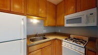 Located at 580 N Park St in Columbus, Ohio, this single-floor unit offers a practical and well-organized layout designed for comfortable everyday living. Throughout the space, durable wood-look plank flooring adds warmth and visual continuity, complemented by clean white baseboards and crown molding that lend a polished finish to each room.

The kitchen is efficiently arranged in an L-shaped configuration, featuring warm honey-toned wood cabinetry that extends to the ceiling for ample storage. Countertops provide functional prep space, and the kitchen is equipped with a gas range, over-the-range microwave, refrigerator, and a stainless steel sink. The neutral gray walls keep the space feeling light and open.

The main living area is bright and open, with natural light filtering through window blinds and a thermostat conveniently positioned on the wall. Crown molding runs along the ceiling, reinforcing the clean, classic aesthetic carried throughout the unit.

The bedroom is a comfortable and airy retreat, highlighted by a ceiling fan with light fixture and a window with blinds that allows natural light to fill the room. The wood-look flooring continues here, maintaining the cohesive design of the space.

The bathroom features a full tub and shower combination enclosed by classic white square tile, providing a clean and timeless look. Overall, this unit delivers a straightforward, functional living environment in a convenient Columbus location.