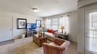 This single-floor residence offers a thoughtfully designed layout that balances comfort and functionality across its key living areas. The living room is a welcoming, light-filled space featuring plush carpeting, large windows with sheer curtains that invite natural light, and ample room for seating and entertainment. A ceiling-mounted light fixture and neutral wall tones contribute to the room's relaxed, inviting atmosphere.

The kitchen is efficiently laid out with warm wood cabinetry, tile flooring, and a full suite of stainless steel appliances including a side-by-side refrigerator with ice and water dispenser, a gas range, and an over-the-range microwave. A peninsula with bar seating provides a convenient casual dining option and additional counter space.

Adjacent to the kitchen, the dedicated dining area features neutral taupe walls and offers room for a full dining set, making it well-suited for everyday meals or entertaining.

The bedroom is generously proportioned with soft carpeting, a ceiling fan, and windows dressed with light, airy curtains that allow natural light to filter through while maintaining privacy. A spacious floor plan provides ample room for substantial furniture.

The bathroom includes a wood-toned vanity with a marbled countertop, a large mirror with overhead vanity lighting, and tile flooring, rounding out a practical and well-finished space throughout.
