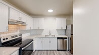 Located at 2948 W Powell Blvd in Gresham, Oregon, this single-floor, 2-bedroom, 2-bathroom home offers a clean, modern aesthetic with thoughtful updates throughout. The open living area features durable gray luxury vinyl plank flooring, a textured ceiling, and a neutral white color palette that creates a bright, airy atmosphere. Large windows allow natural light to filter in, with views of surrounding greenery visible from multiple rooms. A glass-paneled entry door further enhances the sense of openness in the living and dining area.

The kitchen is a standout feature, outfitted with crisp white shaker cabinetry, a classic white subway tile backsplash, light-toned countertops, and a full suite of stainless steel appliances including a range, dishwasher, and refrigerator. Both bedrooms are carpeted in a soft neutral tone, offering a comfortable retreat. The primary bedroom includes a closet with built-in shelving, while windows overlook lush outdoor foliage.

The two bathrooms are well-appointed: one features a tub-shower combination with chrome fixtures, while the other offers a vanity with light wood cabinetry, subway tile backsplash detail, and wood-look flooring. A dedicated closet provides additional storage space, rounding out this well-organized and move-in-ready home.