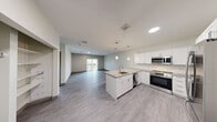 Located at 556 Main St in Falmouth, MA, this thoughtfully designed one-bedroom, two-bathroom residence offers a clean, modern aesthetic throughout its single-floor layout. The open-concept living and dining area flows seamlessly into the kitchen, which features crisp white cabinetry, light quartz countertops, a central island with an undermount sink, and a full suite of stainless steel appliances including a range, microwave, dishwasher, and refrigerator. Pendant lighting above the island adds a refined touch, while light gray luxury vinyl plank flooring unifies the living spaces. A sliding glass door in the living area opens to a private balcony, filling the space with natural light and outdoor views. The bedroom is carpeted for comfort and is brightened by a large window overlooking greenery, with generous closet space featuring built-in wire shelving. The bathrooms are finished in a clean, contemporary style, with one including a glass-enclosed shower and a stacked in-unit washer and dryer for added convenience. Additional storage is provided by a pantry and hallway closet. The overall ambiance is bright, neutral, and move-in ready.