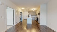 Located at 878 Joseph E Lowery Blvd NW in Atlanta, GA, this single-floor residence offers a thoughtfully designed open-concept layout with modern finishes throughout. The kitchen serves as the heart of the space, showcasing gray shaker-style cabinetry, a classic white subway tile backsplash, and a spacious granite-topped center island with pendant lighting overhead. Stainless steel appliances, including a French door refrigerator with ice maker, a range, and a microwave, complete the well-appointed kitchen. Rich, dark hardwood-style flooring flows throughout the main living areas, adding warmth and contrast to the bright, neutral-toned walls. The living area benefits from natural light through multiple windows and a glass door that opens to the exterior. The bedroom features plush carpeting, a ceiling fan, and a generously sized window that fills the room with natural light. The bathroom is finished with classic white hexagonal tile flooring and full subway tile surround in the tub-shower combination, accented by brushed gold fixtures for an elevated touch. A convenient in-unit stacked washer and dryer is tucked neatly behind louvered closet doors, adding practicality to the overall design. The space balances clean, contemporary aesthetics with functional everyday living.