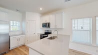 Located at 4086 Silverside Way on Johns Island, SC, this three-story home offers 3 bedrooms, 4 bathrooms, and a well-organized layout spread across three distinct floors. The ground level includes a spacious garage with automatic opener, a water heater, and direct interior access, providing practical utility from the moment you arrive. The main living floor features an open-concept kitchen and living area bathed in natural light from multiple windows. The kitchen is outfitted with crisp white shaker cabinets, a subway tile backsplash, stainless steel appliances including a range, microwave, and refrigerator, and a peninsula with a quartz countertop and undermount sink — ideal for both cooking and casual dining. Light oak hardwood flooring runs throughout the main and upper levels, complementing the clean, neutral palette of the interiors. The upper floors house all three bedrooms, each offering natural light, ceiling fans, and generous proportions. The bedrooms are served by well-appointed bathrooms featuring white cabinetry with quartz counters, tub-shower combinations, and brushed gold hardware accents. Two closets provide ample storage, and multiple staircases connect the floors with ease. The overall aesthetic is modern and move-in ready.