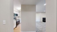 This single-floor, 2-bedroom, 2-bathroom residence offers a practical and comfortable layout across a well-utilized footprint. The open-concept kitchen and living area serves as the heart of the home, where a sleek kitchen features white shaker cabinetry with gold hardware, stainless steel appliances including a refrigerator, range, and over-the-range microwave, and a peninsula with a striking marble-style quartz countertop and an undermount sink — ideal for casual dining or entertaining. Light wood-style flooring runs through the kitchen, transitioning into plush carpeting in the living room, which is anchored by a classic black-surround fireplace and a ceiling fan, creating a cozy and inviting atmosphere. Natural light filters through vertical blinds and windows throughout the space. The primary bedroom is a comfortable retreat with soft carpeting, recessed lighting, and a window with a view of surrounding greenery. The bathrooms are finished with marble-style quartz countertops, white cabinetry with gold hardware, and wood-style flooring. A dedicated laundry area accommodates a full-size side-by-side washer and dryer with overhead shelving for added storage. Two closets and two hallways complete the functional layout of this well-designed residence.