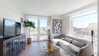 Located at 45 Main St in Yonkers, NY, this contemporary residence offers a thoughtfully designed single-floor layout with modern finishes throughout. The living area is a standout feature, characterized by expansive floor-to-ceiling windows and glass doors that frame sweeping panoramic views of the Yonkers cityscape. Warm hardwood flooring flows throughout the space, complementing the clean white walls and bright, open atmosphere. Natural light pours in from multiple directions, creating an airy and inviting environment.

The kitchen is well-appointed with two-tone cabinetry—high-gloss white upper cabinets paired with rich wood-grain lower cabinets—set against a sleek gray backsplash. Stainless steel appliances, including a gas range and built-in microwave, add a polished, modern touch alongside quartz countertops.

The bedroom is comfortably sized with a built-in closet and direct access to additional rooms, maintaining a clean and functional flow. The bathroom features large-format tile flooring, dark slate wall tiles surrounding the soaking tub and shower, a wood-vanity with an integrated sink, and a wide mirror with overhead lighting.

Overall, the residence conveys a modern urban aesthetic, blending functionality with contemporary design and impressive elevated views.