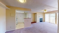 Located at 2736 Mirage Dr in Colorado Springs, Colorado, this single-floor residence offers a practical and comfortable layout with a warm, neutral color palette throughout. The living room serves as the heart of the home, highlighted by a tile-surround fireplace with a classic white mantle and glass doors, plush wall-to-wall carpeting, and a ceiling fan with light fixture overhead. Large sliding glass doors dressed with vertical blinds open to an outdoor space, filling the room with natural light. The kitchen is designed for efficiency, featuring white cabinetry, light countertops, tile flooring, and a pass-through bar that connects it to the living area, creating an open and sociable atmosphere. A range with oven is included among the kitchen appliances. The bedrooms are generously sized, each with soft carpeting, textured ceilings, and windows that bring in natural light. At least one bedroom includes a closet with dedicated storage space. The bathroom is well-appointed with a tub-shower combination featuring a sliding glass enclosure, a single-sink vanity with white cabinetry, tile flooring, and a large mirror. Throughout the home, textured ceilings and warm beige tones contribute to a cohesive and inviting ambiance.