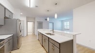 Located at 2200 Ingram Ave in Richmond, Virginia, this single-floor, 3-bedroom, 2-bathroom residence offers a clean, modern design with a cohesive aesthetic throughout. The open-concept kitchen and living area serves as the heart of the home, anchored by a generous island with a white quartz countertop, undermount sink, and pendant lighting above. Gray cabinetry, stainless steel appliances — including a refrigerator, range, microwave, and dishwasher — and bright recessed lighting complete the kitchen's contemporary look. Light-toned hardwood flooring flows seamlessly across the main living areas and all three bedrooms, creating a warm, unified feel. Each bedroom is well-proportioned and filled with natural light from windows fitted with blinds, and ceiling fans add comfort. The spacious primary bedroom offers a generous footprint with ample closet access. Both bathrooms feature a consistent design language with gray vanities, white quartz countertops, brushed nickel fixtures, rectangular mirrors, and light tile flooring. One bathroom includes a tub-shower combination with white tile surround. A dedicated laundry area and seven closets throughout provide exceptional storage. The overall palette of white walls, neutral finishes, and modern hardware gives the home a bright, move-in-ready character.