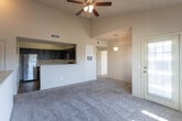 Located at 9150 S Coulter St in Amarillo, Texas, this single-floor residence offers a well-designed layout with a blend of practical finishes and comfortable living spaces. The kitchen is a standout feature, outfitted with rich dark cabinetry that extends to the ceiling for ample storage, light granite-style countertops, stainless steel appliances including a refrigerator, microwave, and range, and durable wood-look flooring. A peninsula counter provides additional workspace and a natural transition into the adjacent living area. The living and dining spaces are characterized by soaring vaulted ceilings that create a sense of openness and volume, with plush wall-to-wall carpeting underfoot. Large windows throughout invite abundant natural light and offer views of the surrounding neighborhood, enhancing the bright and airy atmosphere. A pendant light fixture adds a decorative touch to the dining area. The bedrooms continue the vaulted ceiling design, each featuring generous windows that fill the rooms with daylight and soft carpeting for comfort. The bathroom is finished with dark cabinetry, granite-style countertops, rich wood-look flooring, and a full tub-shower combination with oil-rubbed bronze fixtures, providing a cohesive and polished aesthetic throughout the home.