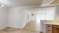 Located at 5700 Ackerfield Ave in Long Beach, California, this single-floor residence offers a clean, functional layout filled with natural light and modern finishes throughout. Light wood-tone flooring runs continuously across the living and bedroom areas, creating a cohesive, bright atmosphere complemented by crisp white walls and textured ceilings.

The open-concept living area is generously sized and connects seamlessly to the kitchen via a pass-through counter opening. Large sliding glass doors dressed with vertical blinds flood the living space with natural light and provide access to the outdoors. A wall-mounted air conditioning unit ensures comfort year-round.

The kitchen is well-appointed with grey cabinetry, a stainless steel side-by-side refrigerator, a gas range, microwave, and light stone countertops. Track lighting above the kitchen highlights the space efficiently.

The bedroom is a comfortable, well-lit room featuring a ceiling fan, vertical blinds on the windows, and the same warm wood-tone flooring found throughout. The bathroom includes a full-size soaking tub and shower combination with clean white surround walls and chrome fixtures.

Overall, the unit presents a refreshed, move-in-ready interior with a neutral palette, practical amenities, and a layout designed to maximize everyday livability in the heart of Long Beach.